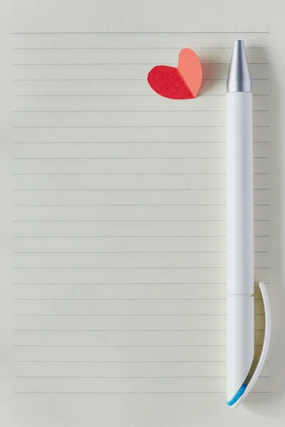 Blank page in notebook, pen and red paper heart. Valentine\'s day card, wedding checklist, love or writing in dairy concept. Flat lay, top view mock up with copy space