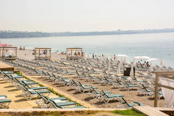 Turizm sezonu açıldı, çok az turist geldi, çok sayıda boş güneşlik ve plaj sandalyesi var. Konyaalti Plajı, Antalya, Türkiye.