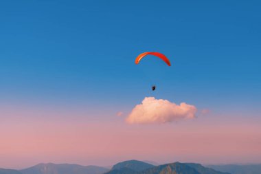 Gün batımında gökyüzüne paraşütle atlamak. Dağların üzerinden uçuyor. Uçak. Bulutun üzerindeki paraglider.