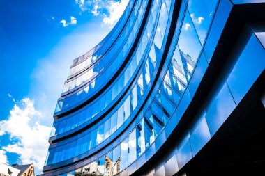Modern mimarinin dış kısmının bir parçası. Alışveriş merkezi. İş merkezi. Beyaz bulutlu mavi gökyüzünün arka planında mat siyah duvarlarda kare pencereler.