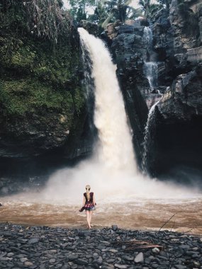 Tropik şelale önünde duran kadın arkadan görünüm