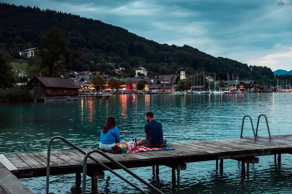 Couple sitting on dock in evening and having picnic