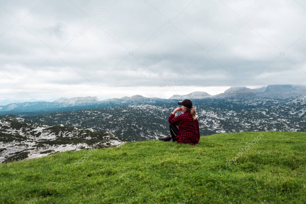 Young woman enjoying mountain view on meadow in Alps