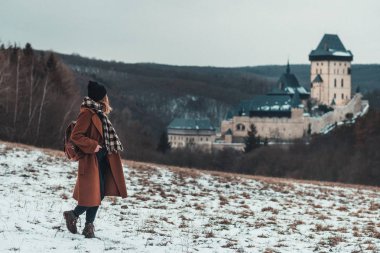 Karlstejn castle, Çek Cumhuriyeti: genç hipster kadın yürüyor doğada, ünlü kalenin içinde mesafe bakarak