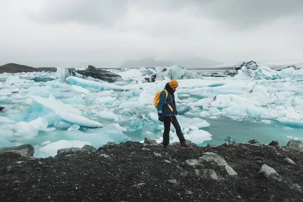 Woman walking on shore of glacier water covered in ice floes in Nordic landscape in Iceland