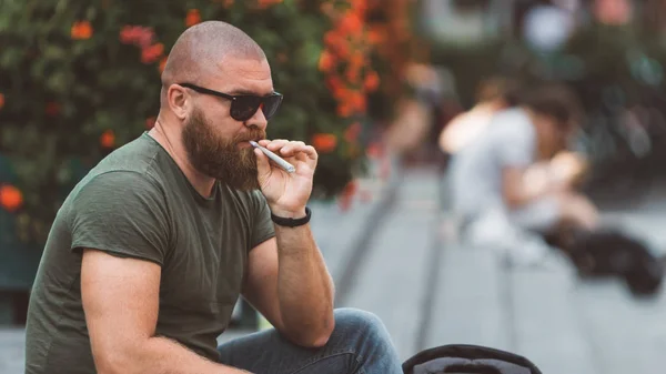 年轻人坐在阿姆斯特丹的公园里 在他的左手吸烟大麻或杂草联合 — 图库照片
