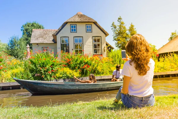 Uma jovem está fotografando uma bela casa em Giethoorn — Fotografia de Stock