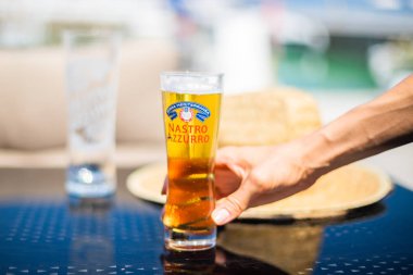 Gabicce Mare, Provincia di Pesaro Urbino (Marche) e / İtalya - 08 03 2018: garson arka planda Meksika Corona şapkalı bir bardak İtalyan bira Nastro Azzurro hizmet vermektedir.