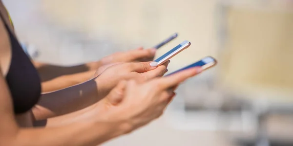 Girls are staying on the beach with smartphones - female hands with mobile phones - social media, troubles with live communication concept