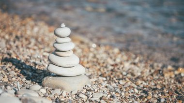 Stones piramide on pebble beach - harmony, meditation, patience and peace of mind concept clipart