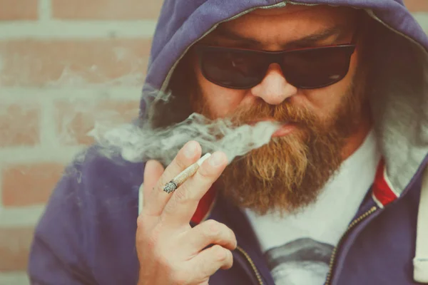 戴着胡须和墨镜的年轻人吸食大麻联合合法化 或合法化 医疗大麻概念 从嘴里看到烟雾的杂草或大麻烟 — 图库照片