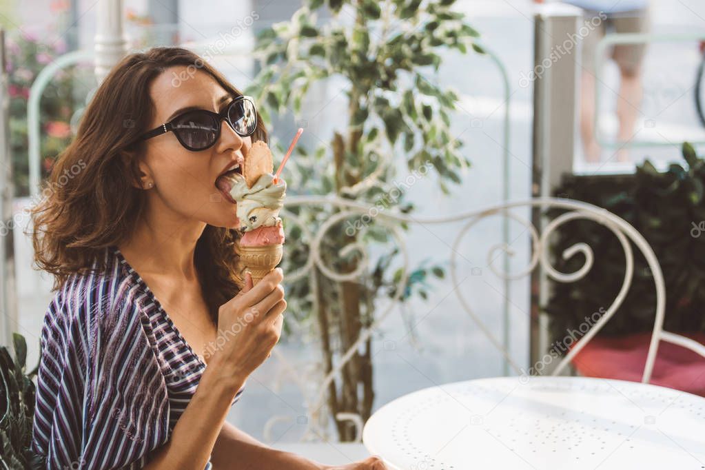Portrait of beautiful happy woman eating (licking) melting artisanal hand made organic ice-cream in Italian cafe - traveling and healthy Mediterranean food (cuisine) concept - picture with copy space
