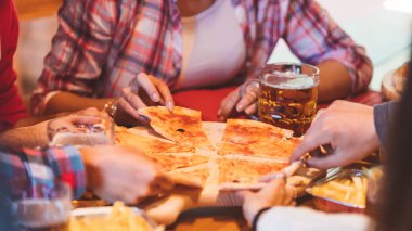Tablo ve çevresinde oturan ve bir dilim alarak genç kolej arkadaş grubu gerçek İtalyan pizza Close-up. En yakın arkadaşlarım pizza ile partide birlikte eğleniyor.