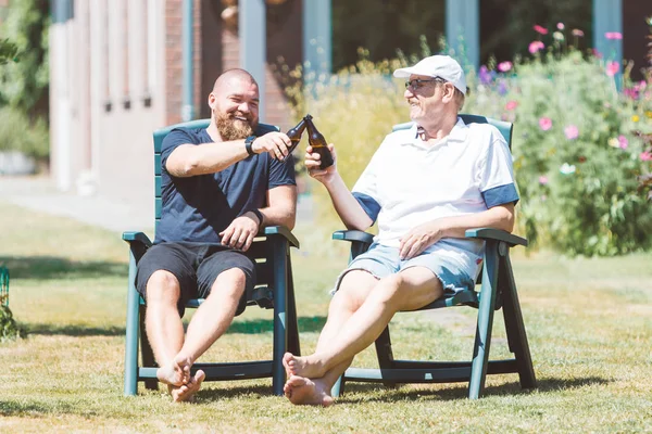 二人の笑みを浮かべて男 老若男女 夏の庭でビールを飲んで最高の友人 父と息子 応援と 家族や父の日のお祝いの概念を一緒に 笑って — ストック写真