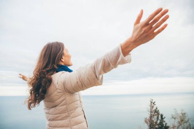 Genç kadın bir uçurumun üzerinden panoramik deniz manzaralı doğa keyif alıyor. Ömür boyu aşk ve Özgürlük kavramı