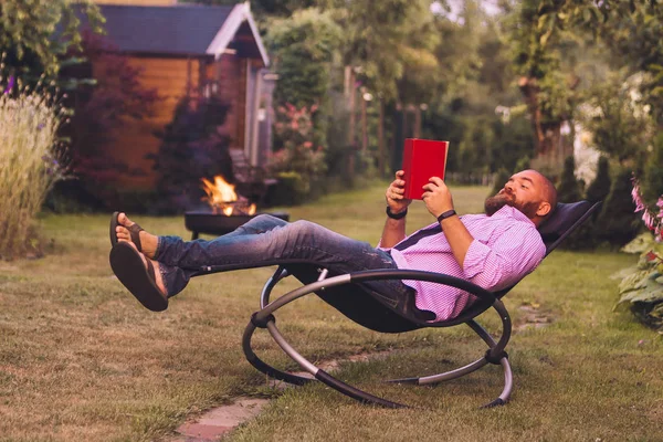 Vousatý Muž Čtení Knihy Houpací Křeslo Rocker Zahradě — Stock fotografie