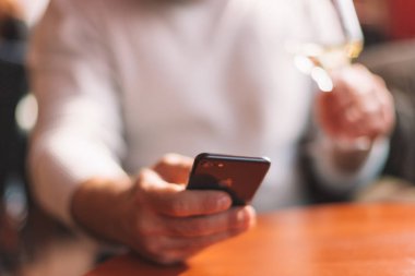 Riccione / İtalya - 03 Aralık 2018 adamın elleri ile apple smartphone (iphone 8) ve bardak beyaz şarap