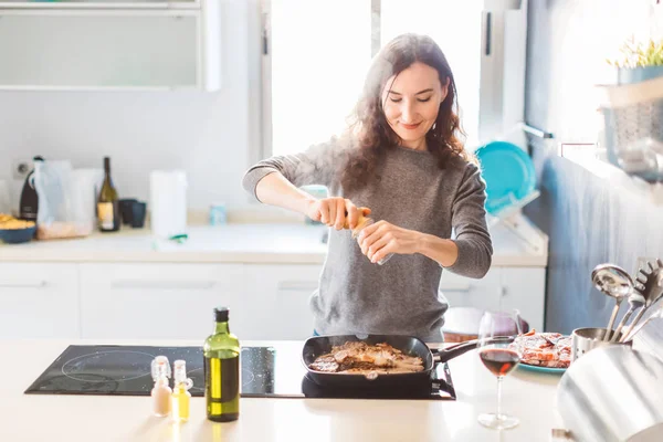 Leende Kvinna Matlagning Köket Lägga Peppar Till Det Grillade Köttet — Stockfoto