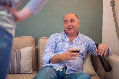 Sarhoş adam karısı ona - alkol bağımlılığı, Aile sorunları ve çatışmaları kavramı kızgın olsa da şişe kırmızı şarap ile kanepede oturuyor.