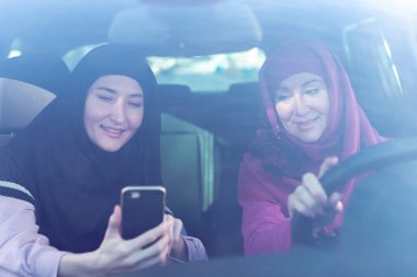 Smartphone vasıl yolu görünümlü iki Müslüman kadın arabada, seyahat