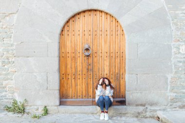 Elleri üzerinde baş aşağı Bend kapalı kapı eşiğinde üzerinde oturan üzgün kız