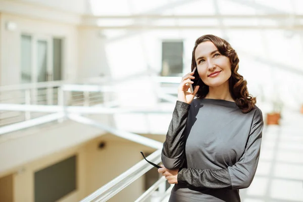 Beautiful elegant business woman with smartphone in her hand is calling or talking on phone