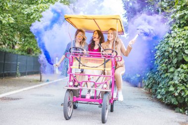 3 girls (young women) riding on a rickshaw and having fun together - crazy party, friendship and ecology concept clipart