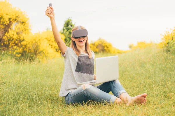 Parkta VR gözlük kullanan genç bir kadın - Artırılmış gerçeklik gözlüğü konseptini test eden blogcu - Oyuncu 3D video oyunu oynarken seviniyor