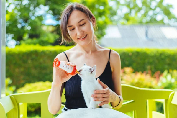 ボトルから白いかわいい子猫をミルクで授乳若い笑顔の女性 ボランティアと家畜の概念 — ストック写真