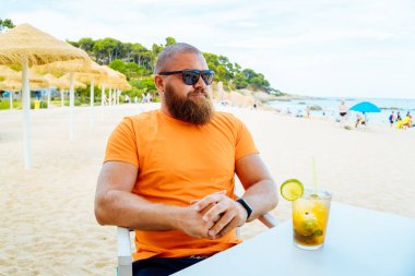Bir plaj kafeveya taze mojito kokteyl bir bardak ile chiringuito oturan genç yakışıklı sakallı adam Portresi