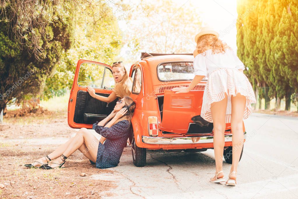 Three girls having a trouble with broken vintage car, travel in Europe and transportation concept