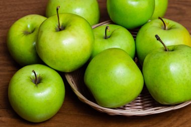 Tahta bir masada sepetteki yeşil elmalar