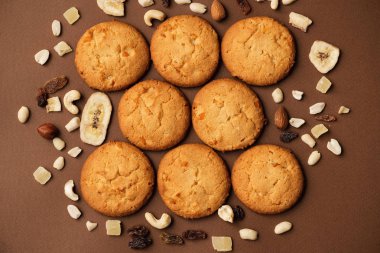 kahverengi arka planda Amerikan kurabiyeleri, kurutulmuş meyveler ve fındık