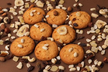 kahverengi arka planda Amerikan kurabiyeleri, kurutulmuş meyveler ve fındık