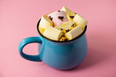 Pembe bir arka planda mavi bardak ve kakao Marshmallow