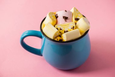 Pembe bir arka planda mavi bardak ve kakao Marshmallow