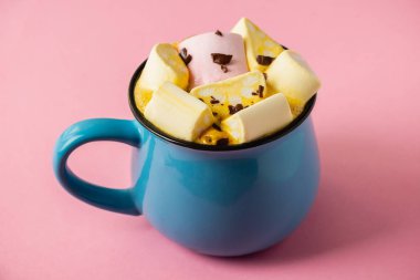 Pembe bir arka planda mavi bardak ve kakao Marshmallow