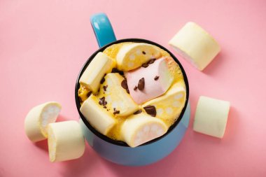 Pembe bir arka planda mavi bardak ve kakao Marshmallow