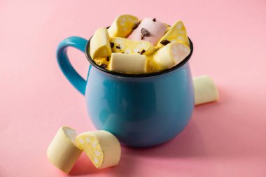 Pembe bir arka planda mavi bardak ve kakao Marshmallow