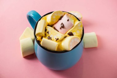 Pembe bir arka planda mavi bardak ve kakao Marshmallow