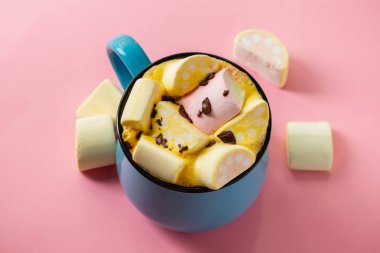 Pembe bir arka planda mavi bardak ve kakao Marshmallow