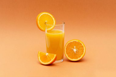 turuncu bir dilim ile turuncu bir arka planda bir bardak portakal suyu
