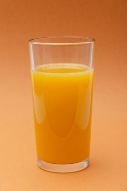 turuncu bir arka planda portakal suyu bir bardak