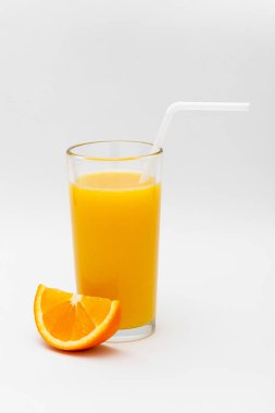 bir bardak portakal suyu ve beyaz bir arka planda turuncu bir dilim