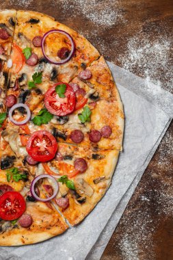 ahşap arka planda parşömen kağıt üzerinde lezzetli pizza