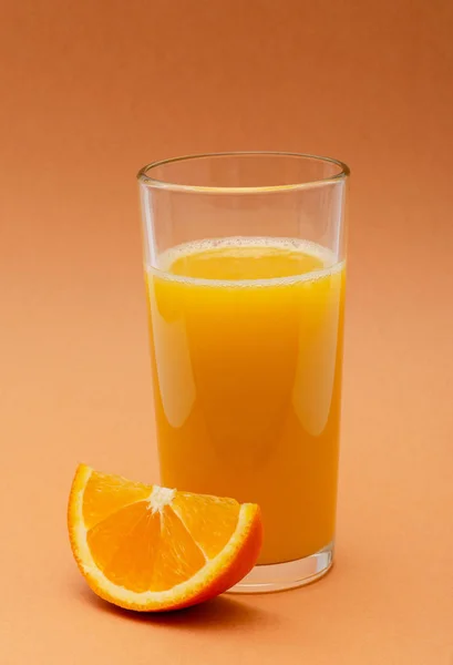 Een Glas Jus Orange Een Oranje Achtergrond Met Een Plakje — Stockfoto