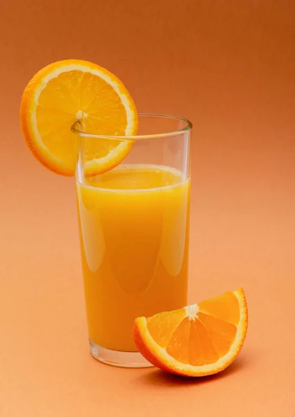 Een Glas Jus Orange Een Oranje Achtergrond Met Een Plakje — Stockfoto