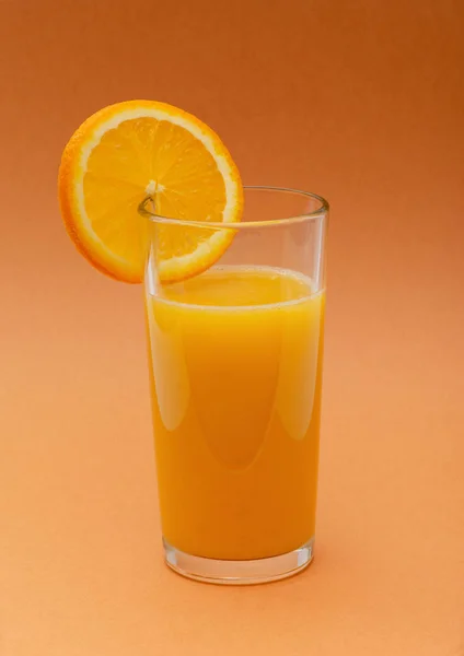 Een Glas Jus Orange Een Oranje Achtergrond Met Een Plakje — Stockfoto