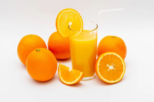glass of orange juice and oranges on a white background