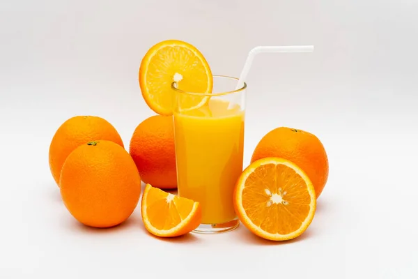 glass of orange juice and oranges on a white background